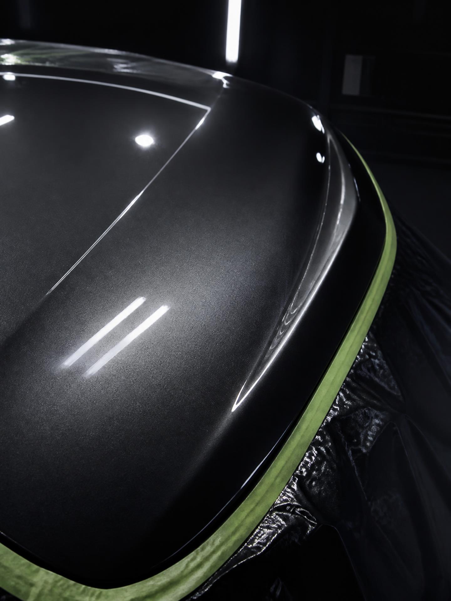 Freshly painted glossy graphite car hood panel under studio lighting at an automotive paint shop