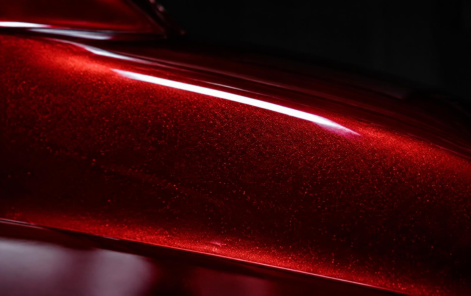 Macro close-up of deep red metallic automotive paint with clear coat and a studio light reflection